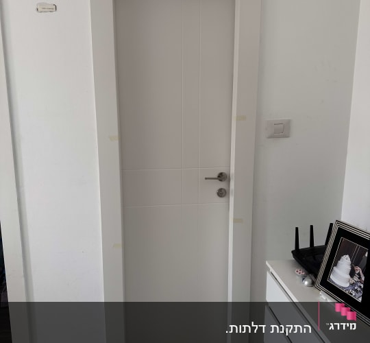 דלת לבנה עם ידית מתכת, מסגרת מודבקת בנייר דבק